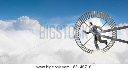 Young businessman running in huge hamster wheel