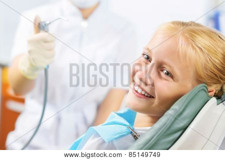 Cute smiling girl in at dentist sitting in armchair