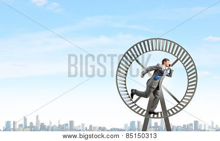 Young businessman running in huge hamster wheel