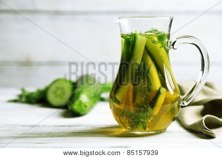 Glass ewer with fresh organic cucumber water on wooden table