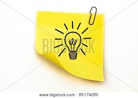 Light bulb against sticky note with grey paperclip