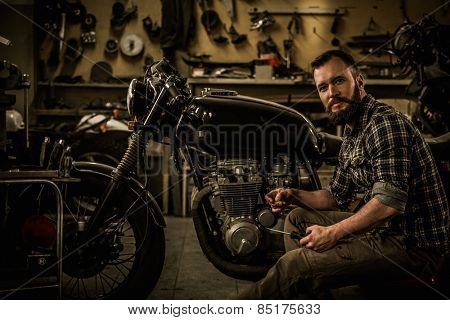 Mechanic building vintage style cafe-racer motorcycle  in custom garage