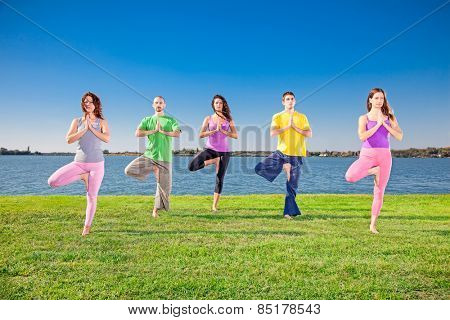 Young people practice Yoga asana on lakeside. Yoga concept.