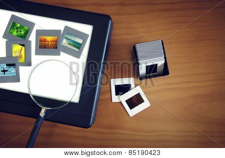 Top view of a light-box with color slides and a magnifier lens over a wooden table