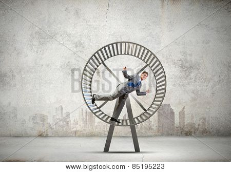 Young businessman running in huge hamster wheel