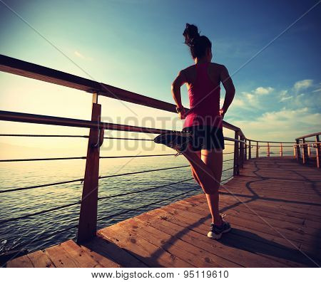 young fitness woman legs running on sunrise seaside trail