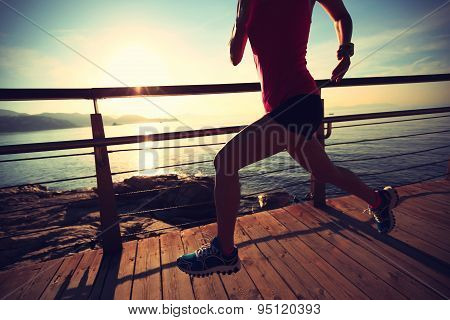 young fitness woman legs running on sunrise seaside trail