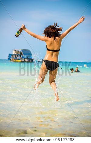 Sexy Asian Thai Girl In Bikini Is Jumping With Joy On The Seashore Of Pattaya Sea With Alcohol Bottl