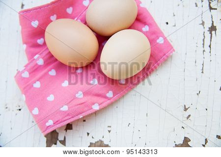Eggs on tablecloth over wooden background