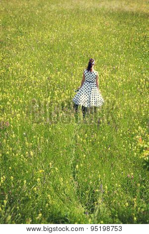 Rockabilly Girl With A White Petticoat Dress Walking Through A Wildflower Meadow