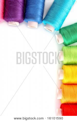 Pile of coloured bobbins of lurex thread isolated on white