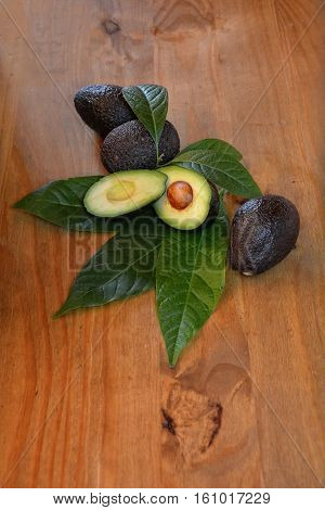 Avocados with sheets on wood (Persea gratissima)