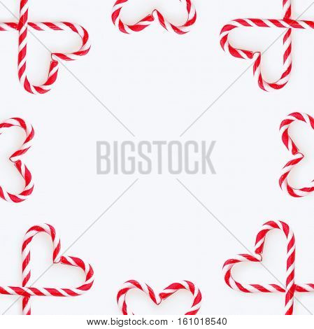 Traditional Christmas candy - candy cane shepherd's staff decorated with red and white stripes. Sandy Cane heart shaped background