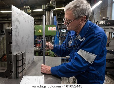 Saint-Petersburg Russia - November 16 2016: Turner miller makes measurements of sheet metal using a planer in the workshop of a machine-building factory machining