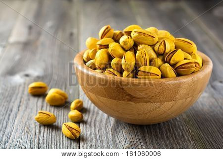 Salted pistachios with saffron in a bamboo plate. Selective focus.