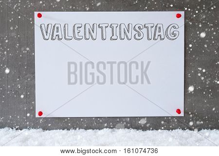 Label With German Text Valentinstag Means Valentines Day. Urban And Modern Cement Wall As Background On Snow With Snowflakes.