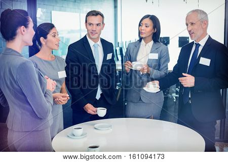 Businesspeople having tea and interacting during breaktime in office
