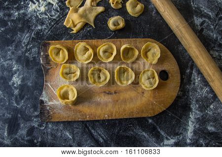 Freshly Prepared Italian Tortellini On Wooden Board Top View
