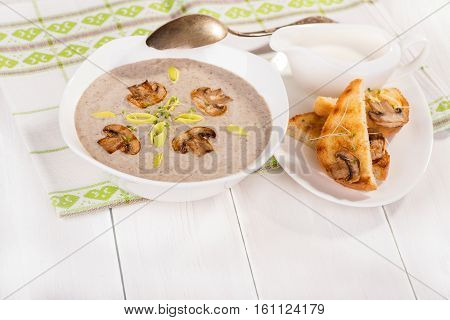 Soup with champignons leek and crispy croutons on white background