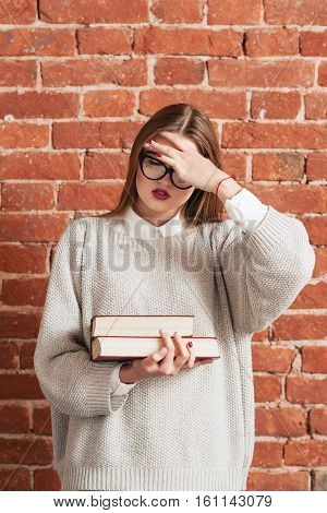 Stressed girl with books forgot something important. Desparate woman girl covering her face with hand. Stress, education, bad memory, tiredness concept