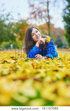 Young Woman On A Fall Day, Laying On The Ground With Colorful Autumn Leaves