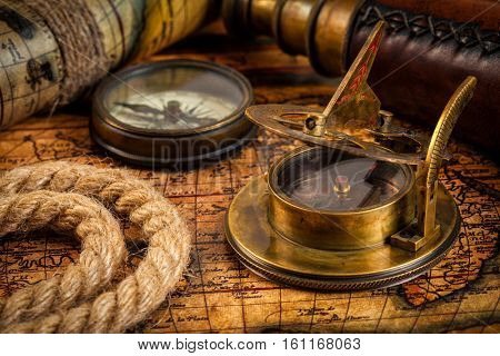 Travel geography navigation concept background - old vintage retro compass with sundial, spyglass and rope on ancient world map