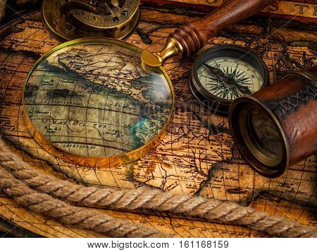 Travel geography navigation concept background - old vintage retro compass with sundial, spyglass and rope on ancient world map