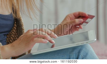 Young woman buying goods from the internet and entering number security code from credit card on digital tablet. Online, technology and internet concept