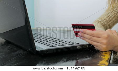 Close up shot. Young woman buying goods from the internet and entering number security code from credit card on laptop. Online, technology and internet concept.