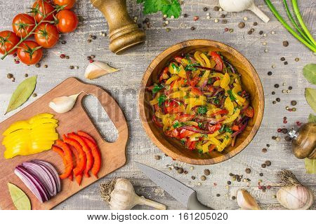 Ingredients for food onion pepper garlic and utensils on a wooden table. A top view of a plate of vegetables greens for copy space