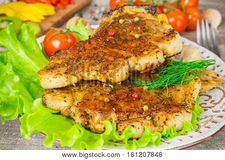 Pork steak with a fork lettuce tomatoes and dill close-up view. Grey food background on wooden table