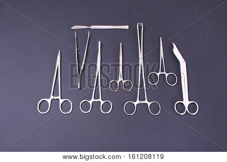 surgical instruments and tools including scalpels, forceps and tweezers arranged on a table for a surgery.