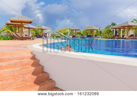 Cayo Guillermo island, Iberostar Playa Pilar hotel, Cuba, June 28, 2016, beautiful inviting view of comfortable cozy swimming pool with smiled little girl relaxing swimming and enjoying her vacation