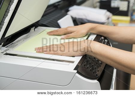 woman hands putting a sheet of paper into a copying device