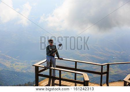 CHIANG MAI THAILAND - 06 NOVEMBER 2016 - Unidentified tourist takes his own portrait photograph (selfie) with his mobile phone at Kew Mae Pan panoramic vantage point.
