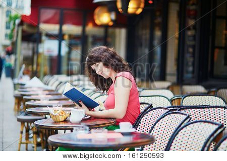 Girl Drinking Coffee And Reading A Book In Parisian Cafe