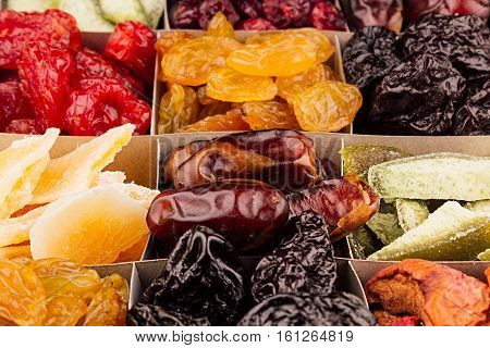 Assortment of dried fruits closeup background in square cells. Decorative pattern of dry exotic fruit. Top view.
