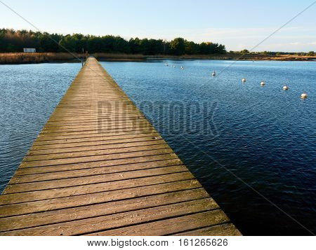 Empty wooden mole on blue lake wharf for hired boats in marina. Ready for trip ships.