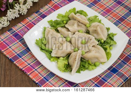 Dumplings with minced chicken on a plate with fresh herbs and peas