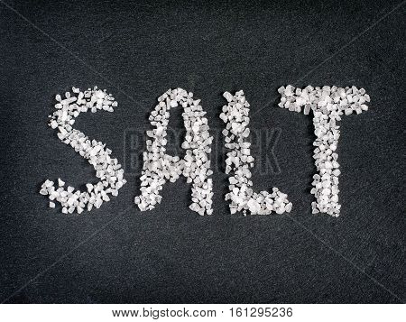 Salt word from coarse sea salt on stone. Flat lay or top view