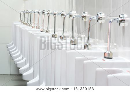 The many white toilet in the public rest room.