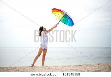 Young women jumping with umbella and happy on the beach. Travel and Vacation. Freedom Concept