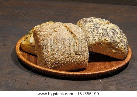 Various types of bread rolls cakes bun in a basket on a rustic wooden surface