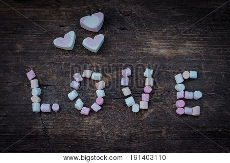 Word LOVE from mini marshmallow on an old rustic wooden background. Romantic love background. Marshmallow concept. Valentine's day card. Valentines day background.