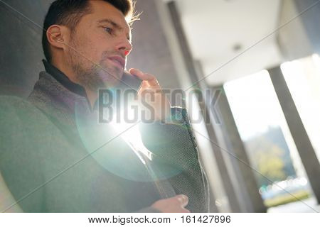 Businessman leaning on wall talking on phone