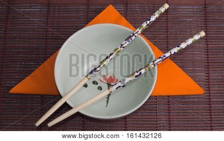Bowl with chopsticks on a brown background