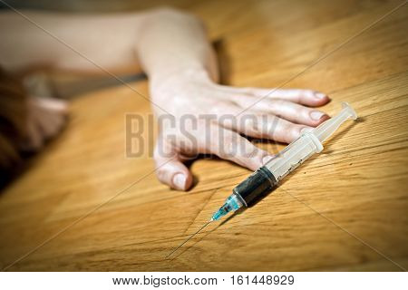 Syringe with heroin in front of drug addict female.