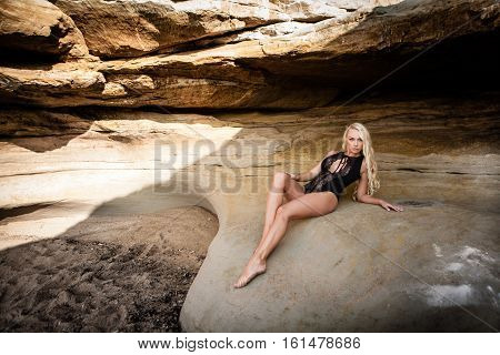 Sexy blond girl in black bikini posing on a beach