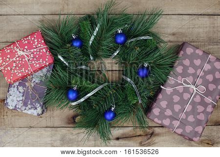 Christmas wreath with decorations and festuve vintage gifts on wooden background.