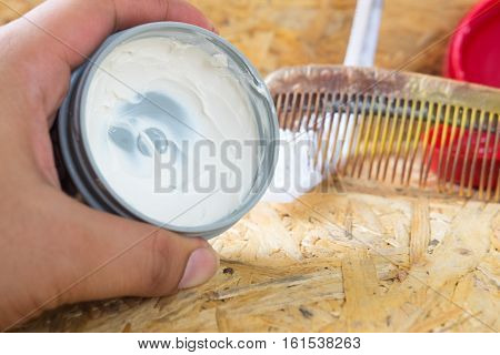 Pomade for hair styling with comb on wood background